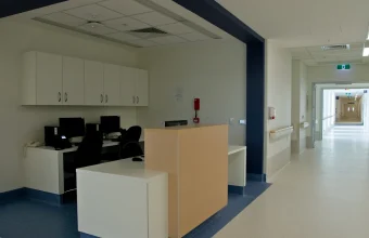 An empty hospital ward reception and nursing workstation with computers and a long corridor beyond, at Fiona Stanley Hospital in Perth, Australia