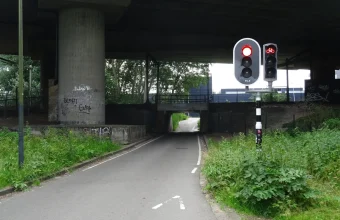 A single-lane road under a railway bridge in Rotterdam where traffic lights show red so that only one direction passes at a time