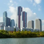 Skyscrapers in Yeouido, the Seoul financial district, above trees on the Han River under a blue sky