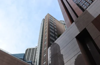 Street-level upward view of the Monetary Authority of Singapore building and neighbouring office towers under a pale sky