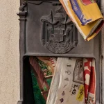 Google Stops Accepting Product Bug Reports for Its Open-Source Bounty, Citing Automated Submissions An ornate cast-iron wall mailbox with its door hanging open, stuffed with colorful flyers and a yellow flyer bulging out of the top slot