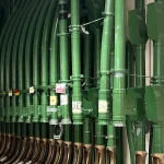 Rows of green pneumatic tubes with handwritten destination labels ending in brass outlets in the National Library of Australia’s tube system