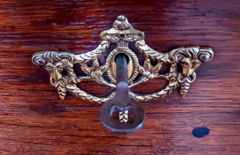 Brass decorative keyhole plate on a wooden drawer with a key inserted in the lock
