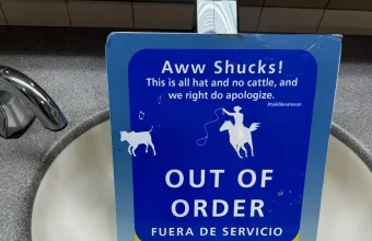 An out-of-order sign standing in an airport sink basin, with a title, a friendly explanation and a Spanish translation, like the members of an error response