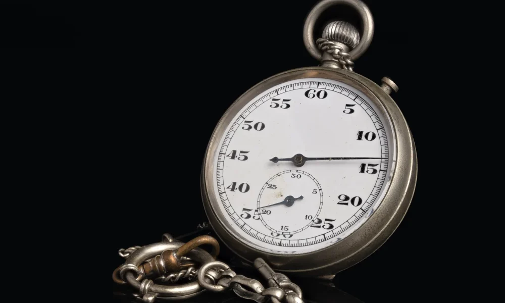 Vintage silver stopwatch with a chain on a black background, its dial showing seconds from 5 to 60