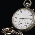 Vintage silver stopwatch with a chain on a black background, its dial showing seconds from 5 to 60