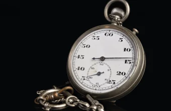 Vintage silver stopwatch with a chain on a black background, its dial showing seconds from 5 to 60