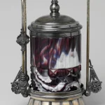 Victorian silver-framed glass pickle jar with a swirled purple and white body and a domed lid against a grey background