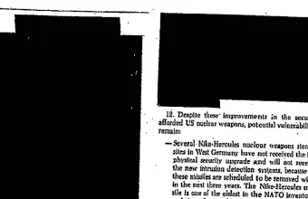 A declassified document page with large black redaction blocks covering most of the text