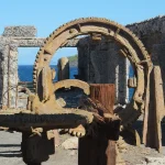 Heavily corroded cogwheels and a rusted ring gear inside an abandoned sulphur factory beside the sea on White Island