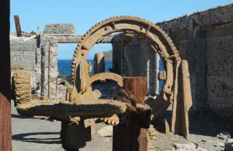 Heavily corroded cogwheels and a rusted ring gear inside an abandoned sulphur factory beside the sea on White Island
