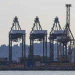 Silhouetted container gantry cranes lined up along a cargo terminal in Singapore