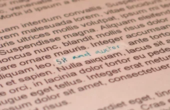 Printed page of text with a white strip of correction fluid and a handwritten correction in blue ink