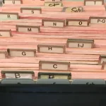 Open card-index filing box with alphabetical divider tabs from A to Z, a physical index for jumping to one entry instead of reading every card