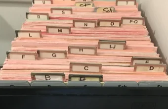 Open card-index filing box with alphabetical divider tabs from A to Z, a physical index for jumping to one entry instead of reading every card