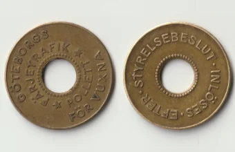 Two brass Gothenburg ferry tokens, front and back, each with a round hole in the middle, on a plain light background