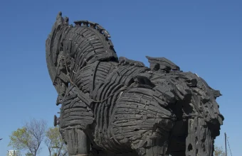 Weathered wooden replica of the Trojan horse standing against a clear blue sky on the Çanakkale waterfront in Turkey