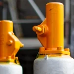 How to Add Backpressure and Load Shedding to a Python Service Before Overload Takes It Down Two orange safety relief valves on grey pressure vessels in an industrial plant
