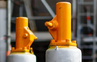 Two orange safety relief valves on grey pressure vessels in an industrial plant