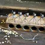 Wooden mousetrap with five spring-loaded traps set over drilled holes, with scattered grain beside a sack in a mill at Malbork