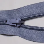Close-up photo of a gray zipper where the slider pulls two rows of teeth together into one