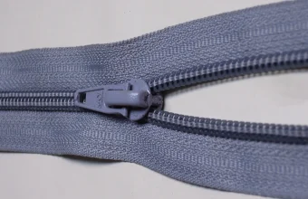 Close-up photo of a gray zipper where the slider pulls two rows of teeth together into one