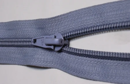 Close-up photo of a gray zipper where the slider pulls two rows of teeth together into one