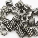 A pile of small stainless steel coil springs lying on a white background